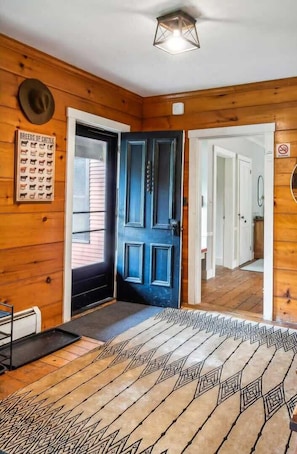 Interior de madera con una puerta azul, un cartel que muestra 'Breeds of Cattle' y una alfombra estampada.