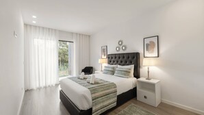 Un dormitorio moderno con una cama grande, una mesita de noche, una silla y vistas al exterior.