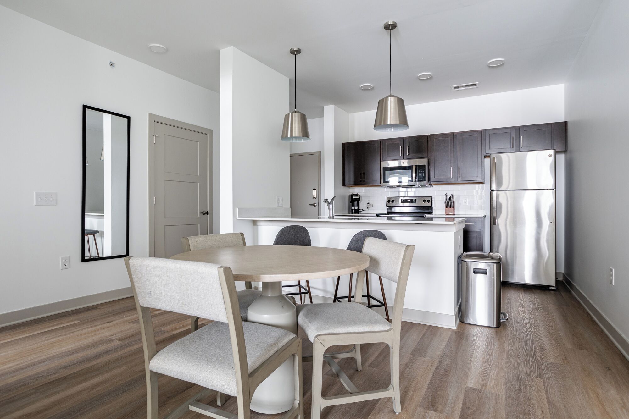 A modern kitchen with a central island, stainless steel appliances, and pendant lighting.