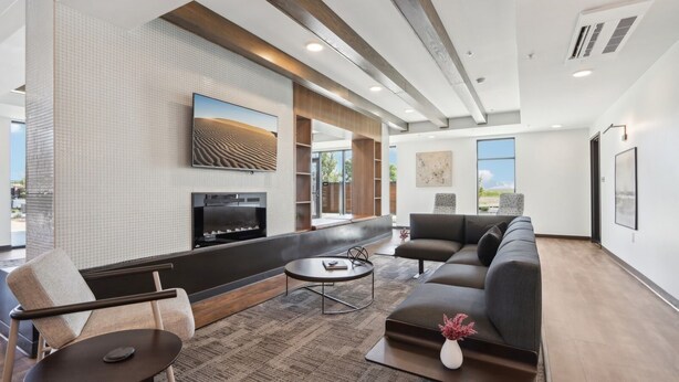 A modern living room with a large flat-screen TV, a sofa, a coffee table, and a fireplace.