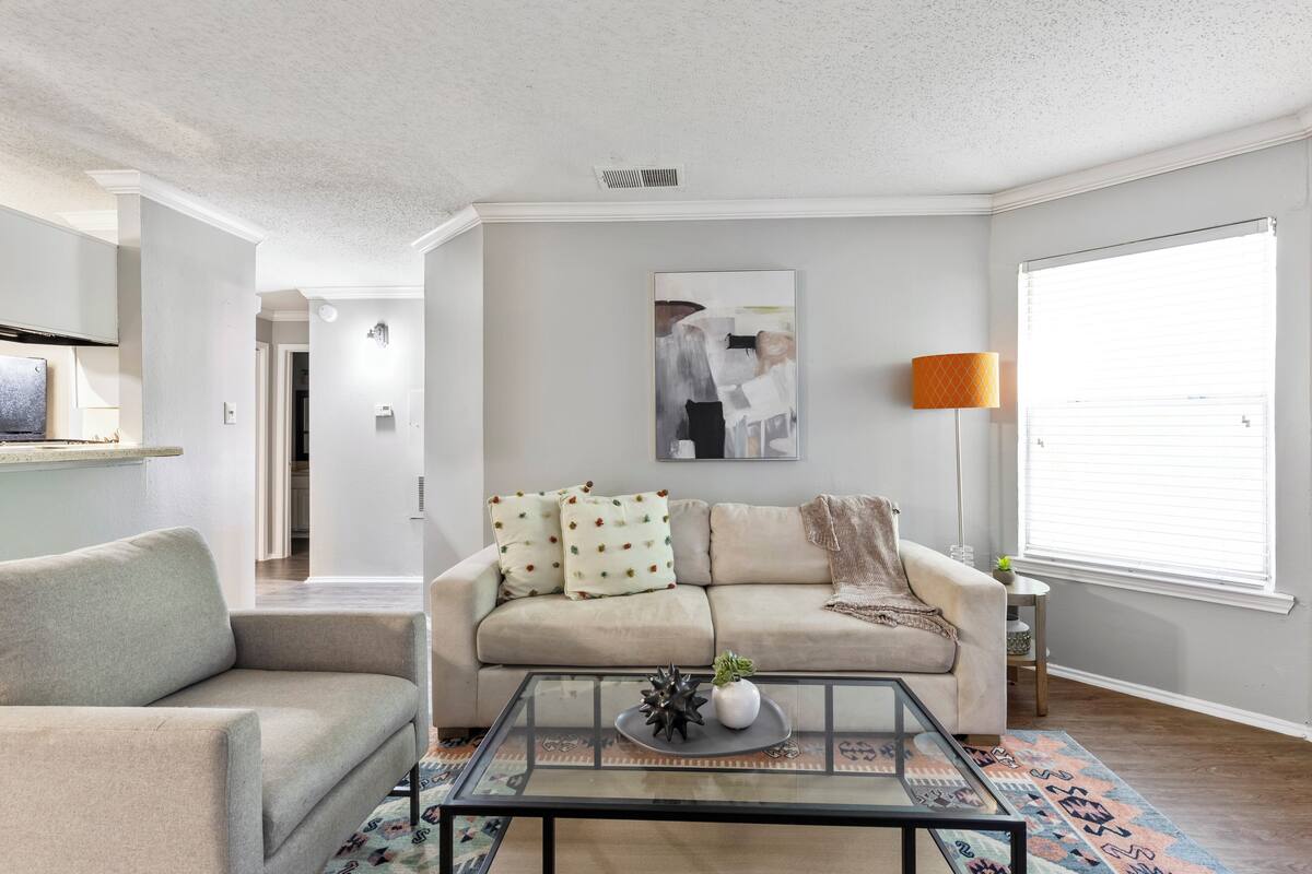 Un salon avec un canapé, une table basse et un tableau accroché au mur.