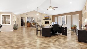 A spacious living area with a fireplace, dining table, and office space. - Landing Grand Prairie (Grand Prairie)
