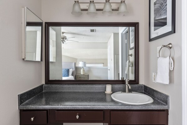 A bathroom with a large mirror, a sink, and a ceiling fan. - Landing Grand Prairie (Grand Prairie)