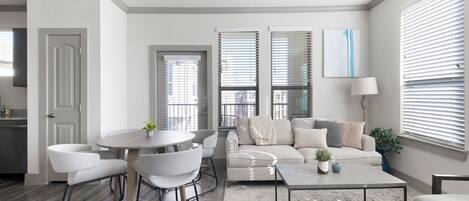 A modern living room with a round table, two armchairs, a sofa, and a coffee table.