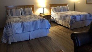 Ein Hotelzimmer mit zwei Betten, Holzboden und Nachttischlampen.