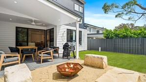 A modern patio with outdoor furniture, a barbecue grill, and a fire pit.