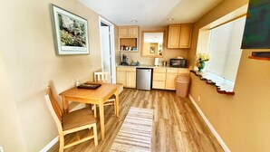 A compact kitchen with wooden cabinets, a built-in oven, and a window with blinds.