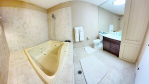 A bathroom with a large bathtub, a toilet, a sink, and a shower.