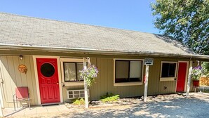A motel with a red door, a sign indicating the office, and a gravel driveway.