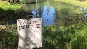 A welcome sign for Lake Cosaltite Ranch with a clear pond in the foreground. - Augustino Vineyard Winery Cabin Cave Junction (O'Brien)