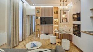 Ein modernes Wohnzimmer mit Flachbildfernseher, Holzvertäfelung und einem Essbereich mit Tisch für zwei Personen.