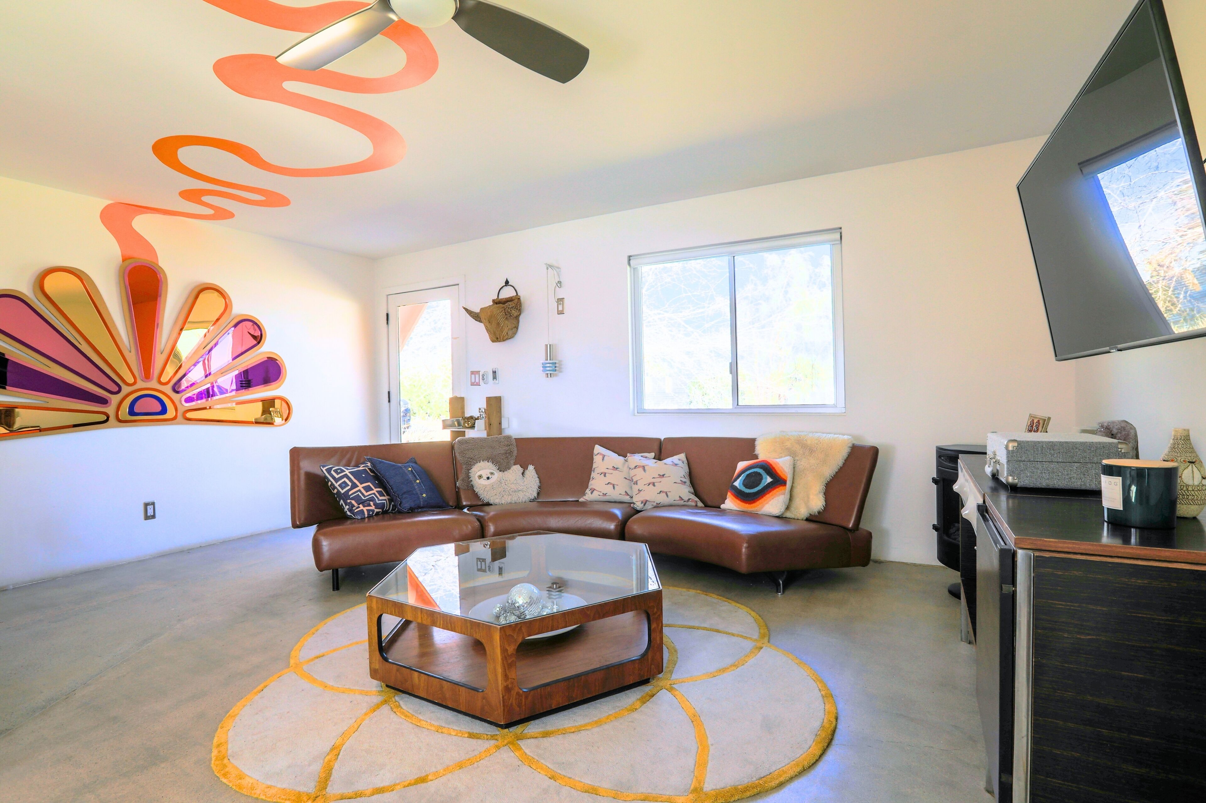A modern living room with a sectional sofa, a glass coffee table, and a ceiling fan.