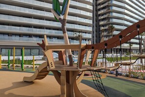A playground with climbing structures and a building in the background.