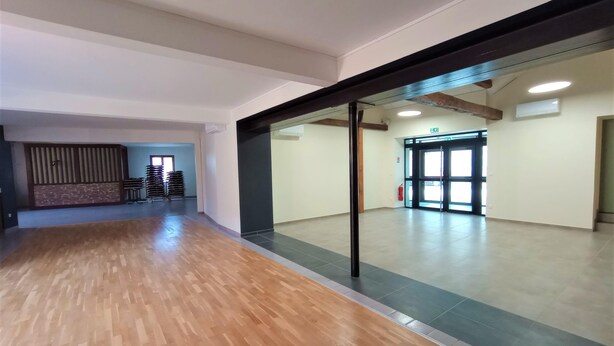 A spacious room with a wooden floor and a large mirror reflecting the interior.