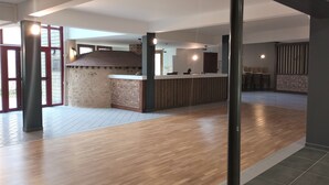 A spacious lobby with a reception desk, a wooden floor, and a view of the outside.