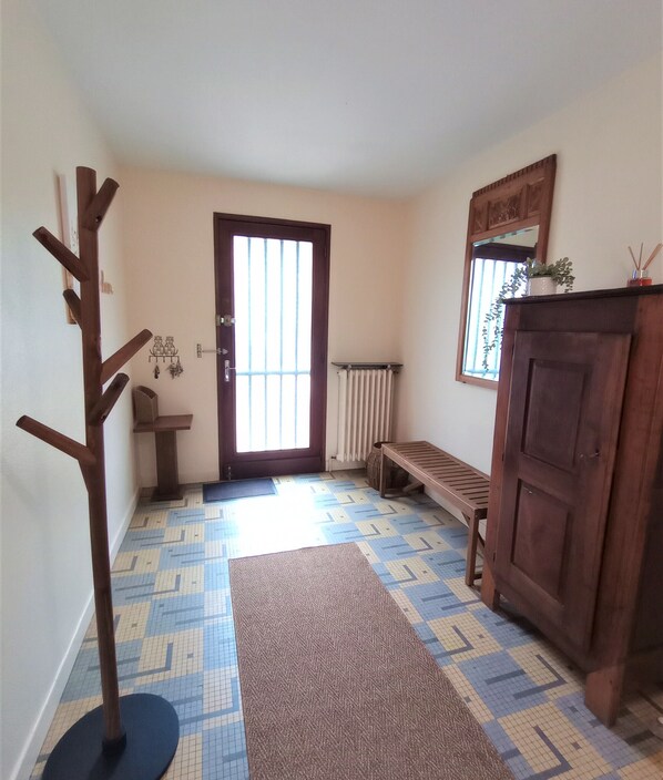 A hallway with patterned flooring, a wooden coat rack, a bench, and a cabinet.