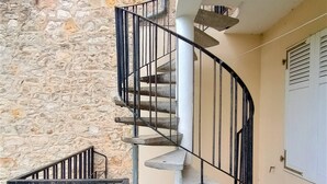 A spiral staircase with a stone wall backdrop, a concrete floor, and a metal railing. - Le Florin d'Or - Bords de Creuse (Saint-Gaultier)