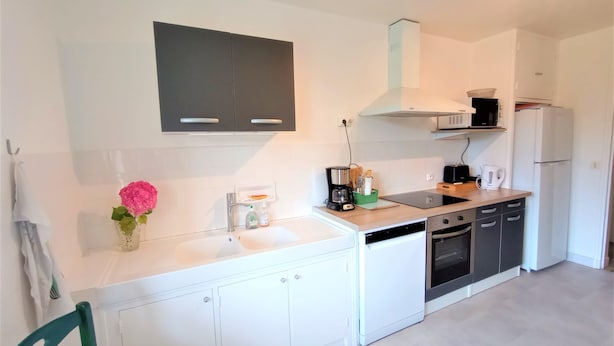 A modern kitchen with white cabinets, a black stove, and a white refrigerator. - Le Florin d'Or - Bords de Creuse (Saint-Gaultier)