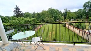 A balcony with a table and chairs, a view of a well-maintained lawn, and a stone wall. - Le Florin d'Or - Bords de Creuse (Saint-Gaultier)