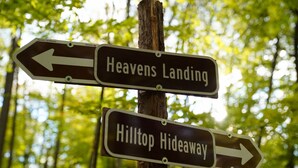 Un poste indicador con flechas señalando a 'Heavens Landing' y 'Hilltop Hideaway'.