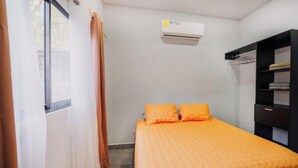 A bedroom with a bed, an air conditioning unit, a wardrobe, and a window with curtains. - Villa Milu, Pool, Avellanas (Tamarindo)