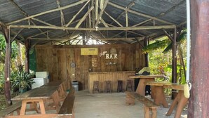 A rustic outdoor bar with wooden benches and a counter.