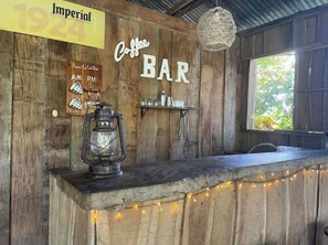 Un bancone di legno rustico con una lanterna vintage, una targa con su scritto "Imperial 1924" e un cartello che indica "Coffee BAR".