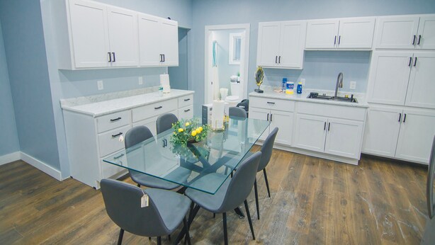 A modern kitchen with white cabinets, a glass dining table, and a wooden floor. - Fully Furnished 1st Floor Retreat, Comfort Awaits (Lewiston)
