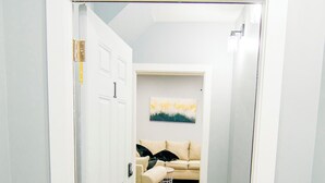 En hall som leder till ett vardagsrum med en beige soffa och en tavla på väggen.