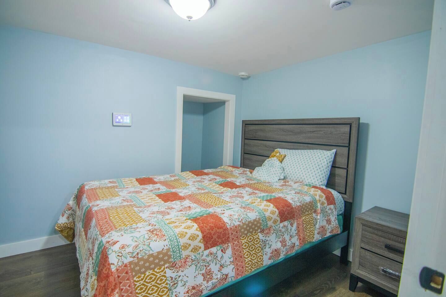 Un dormitorio con una cama, una mesita de noche y un cabecero de madera.
