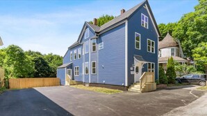 Une maison à deux étages avec un porche à l’avant, une allée et une cour clôturée.