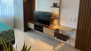 A modern bedroom with a TV, bedside table, and a chair. - Apartment Hotel estelar (Barranquilla)