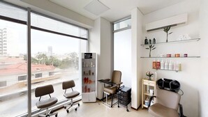 A modern salon with large windows, a reception desk, and shelves with hair products. - Apartment Hotel estelar (Barranquilla)