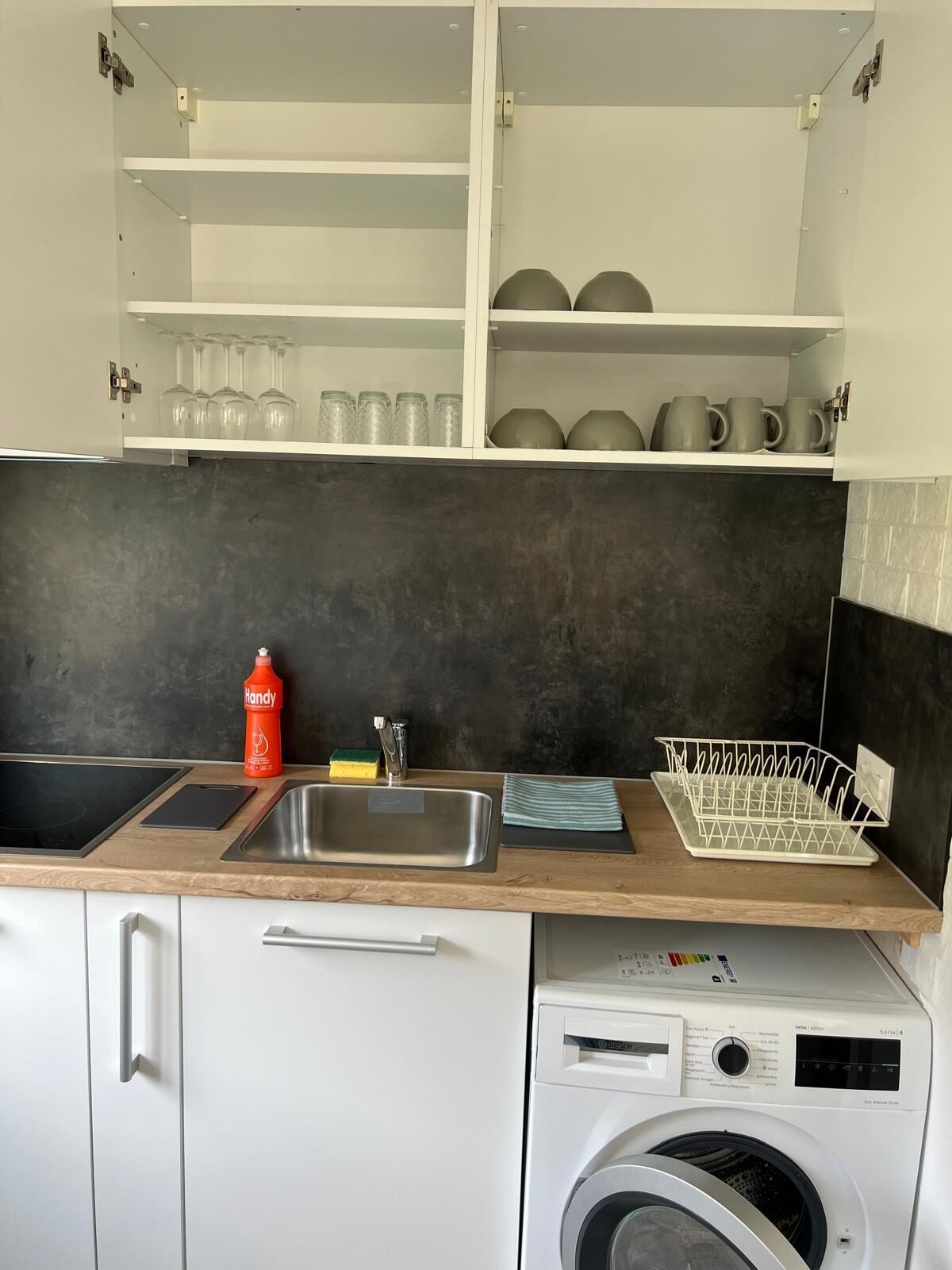 A kitchen with a built-in dishwasher, a sink, and a countertop with a dish rack.