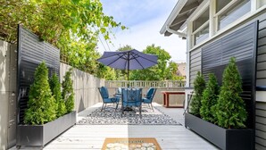 A patio with a table and chairs, a welcome mat, and potted plants.