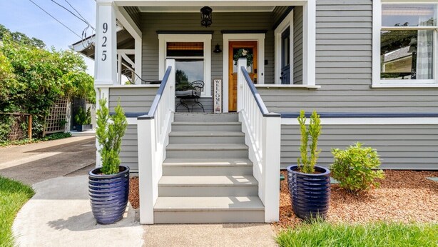 A two-story house with a front porch, a staircase, and potted plants.