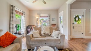 A living room with a beige sofa, a ceiling fan, a fireplace, and a view through a window.