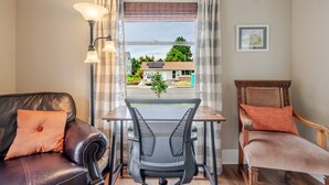 A room with a leather sofa, a wooden chair, a dining table, and a view of the outside.