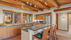 A modern kitchen with wooden cabinets, a granite countertop, and a stainless steel refrigerator. - Casa Serenata - Gated Pueblo Retreat Near Opera, Views + Office - Monthly (Santa Fe)