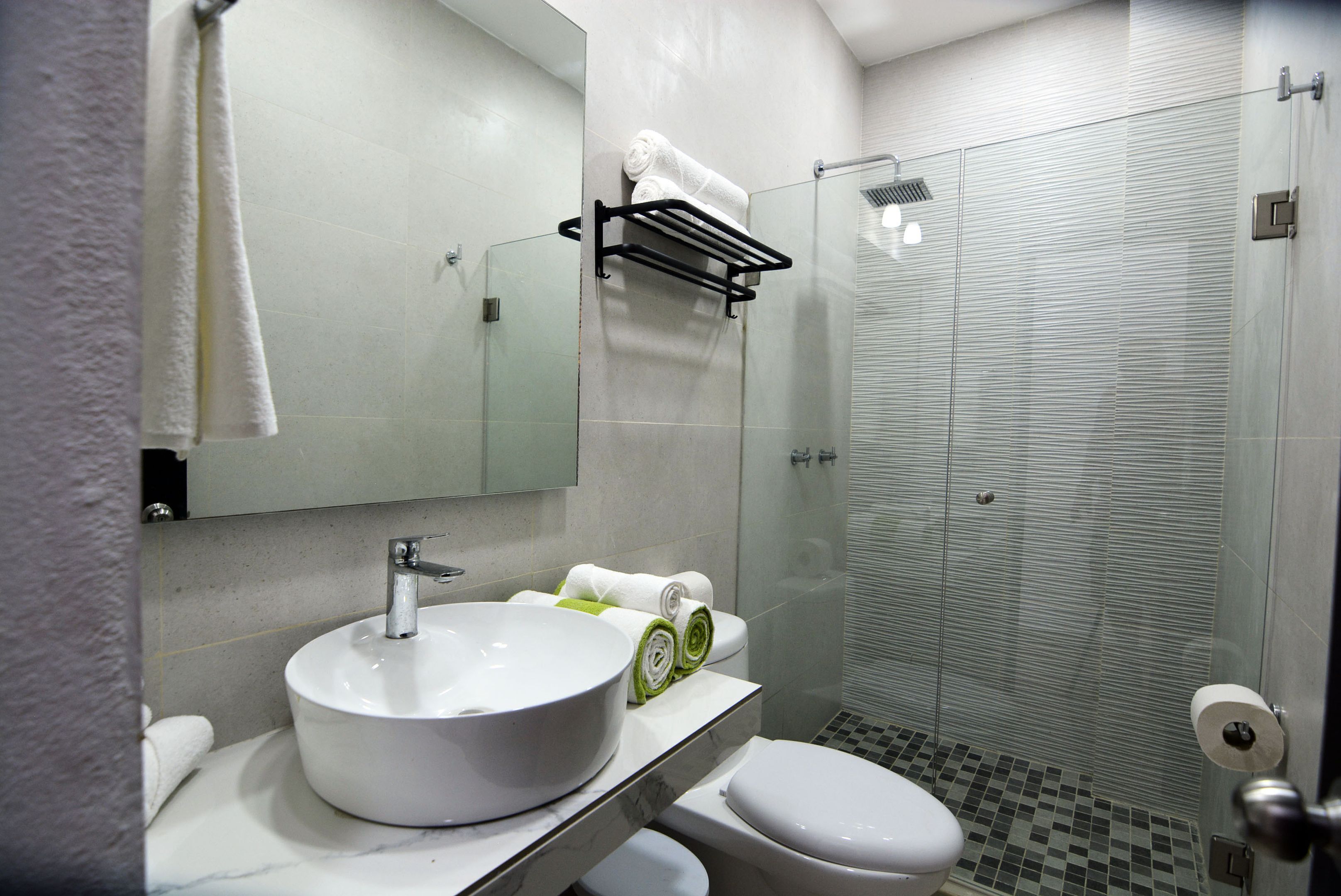 Un baño moderno con lavamanos, inodoro y cabina de ducha de vidrio.