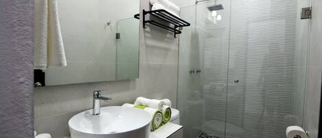Un baño moderno con lavamanos, inodoro y cabina de ducha de vidrio.