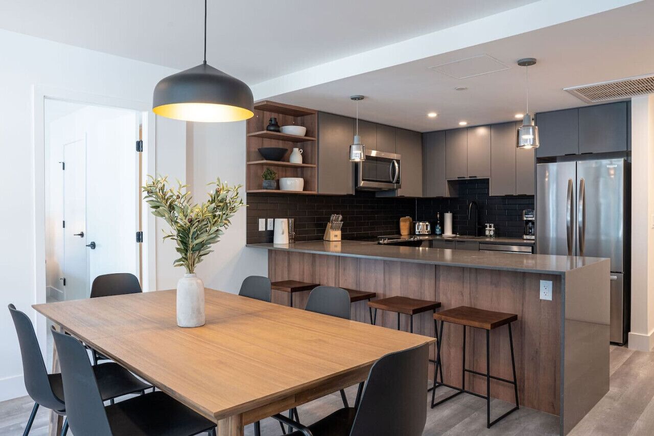 A modern kitchen with a central island, dark cabinetry, and stainless steel appliances.