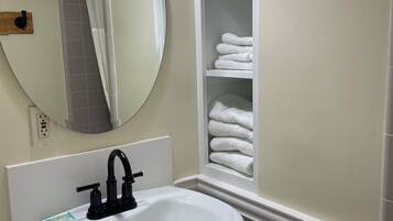 A bathroom with a white sink, a round mirror, and a towel rack.