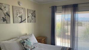 Un dormitorio con una cama, un mesita de noche y tres cuadros de flores colgados en la pared.