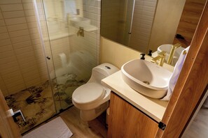 A bathroom with a glass shower enclosure, a toilet, and a sink with a mirror above it.