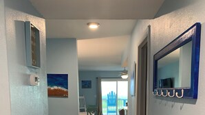 A hallway with a bed, a chair, a painting, and a view of the outside. - Beach Lovers, Oceanview, Cute 1 BR, 2 full BA condo in Surf City sleeps 5 (Surf City)