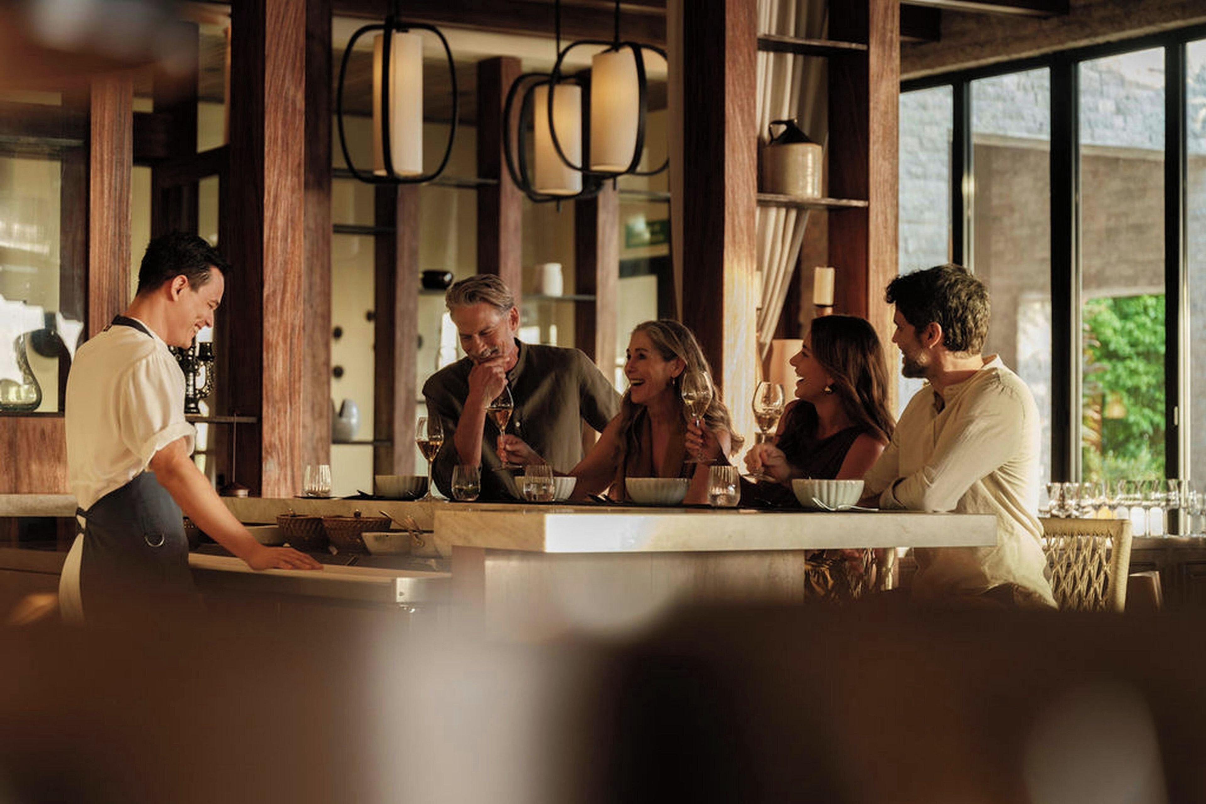 Un restaurant doté d’un bar, de grandes fenêtres et de luminaires suspendus.