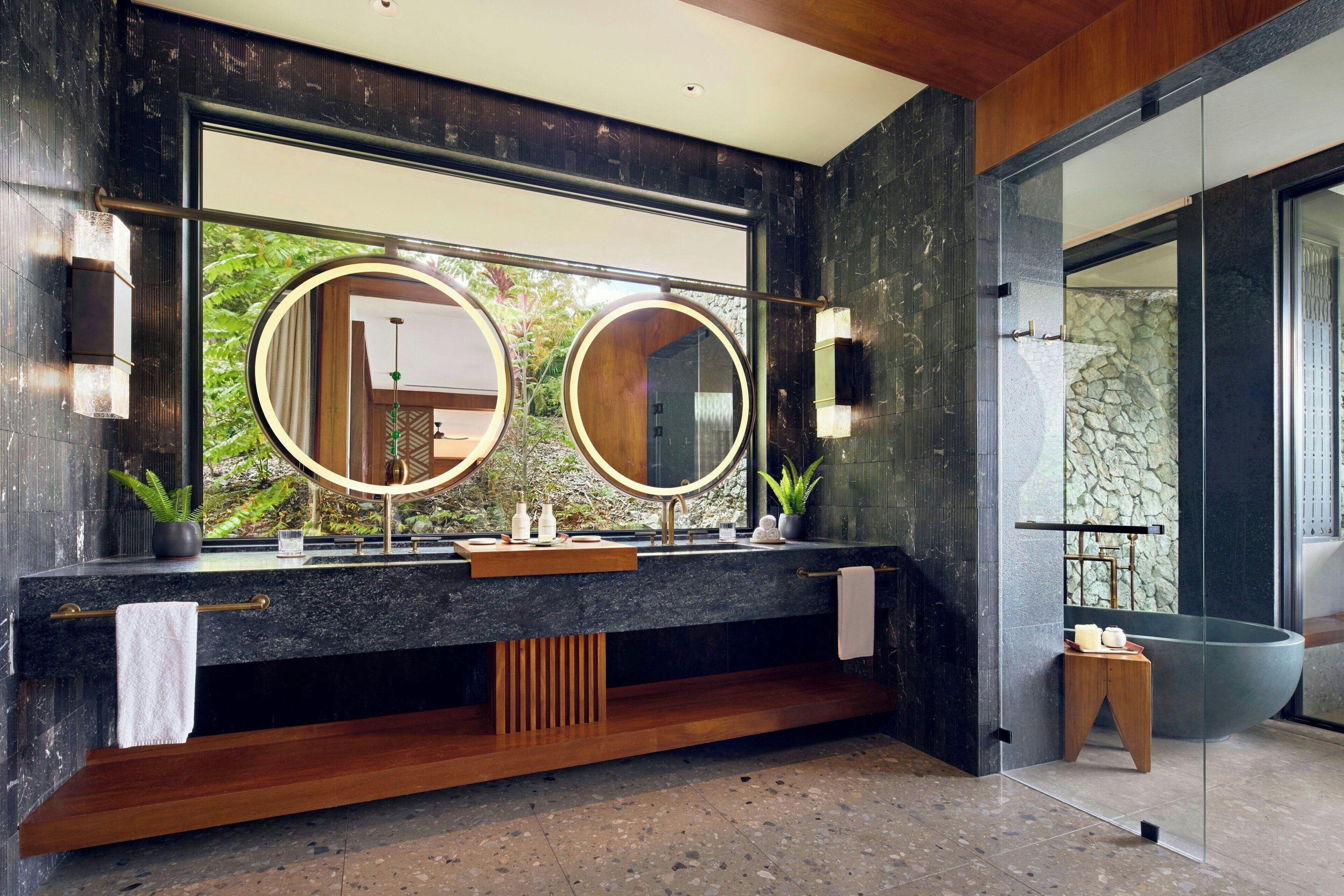 A modern bathroom with a large mirror, a bathtub, and a wooden vanity.