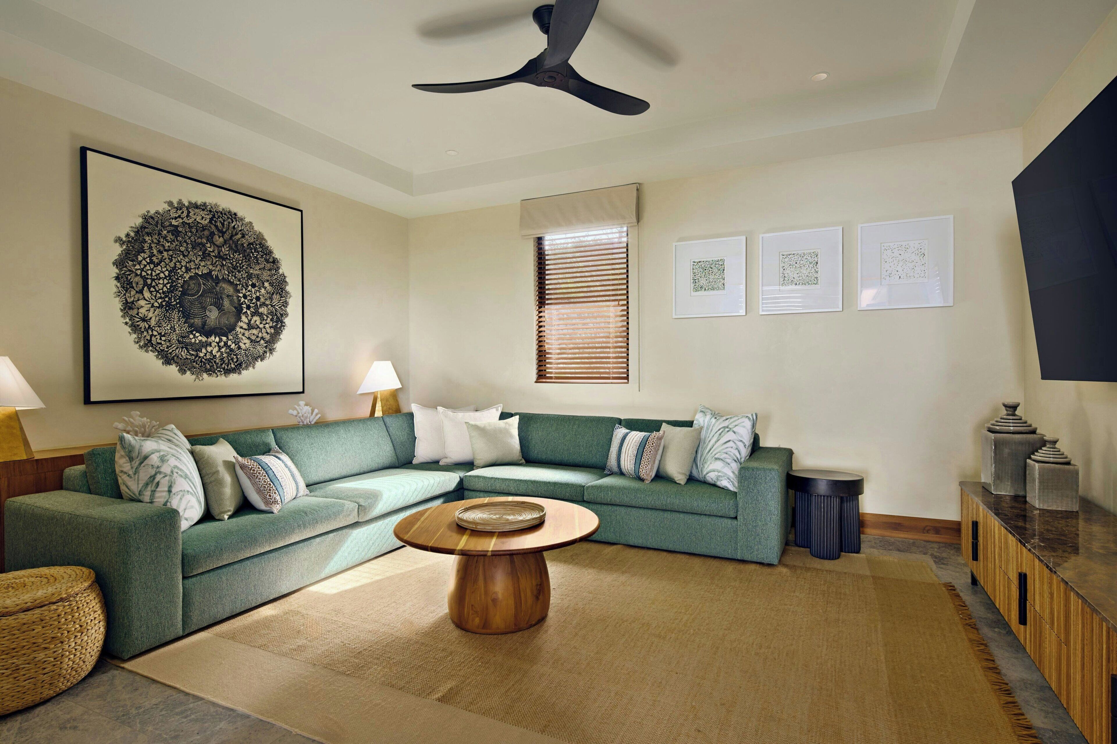 A modern living room with a sectional sofa, a round wooden coffee table, and a ceiling fan.