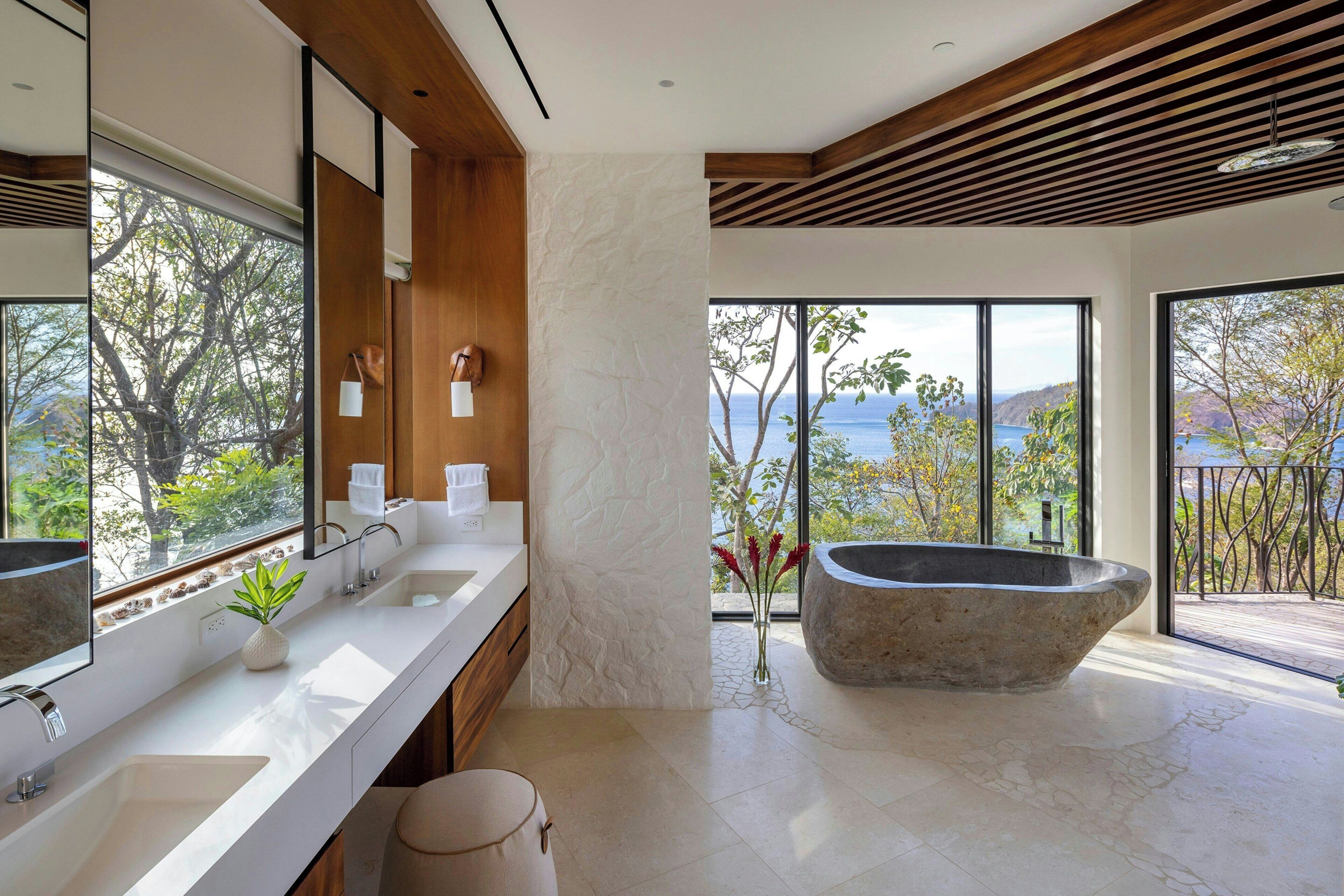 A modern bathroom with a large bathtub, a double sink, and a large mirror.